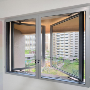 A pair of open casement windows in a room, secured with cat mesh for windows, overlooks a cluster of high-rise apartment buildings and green communal areas.